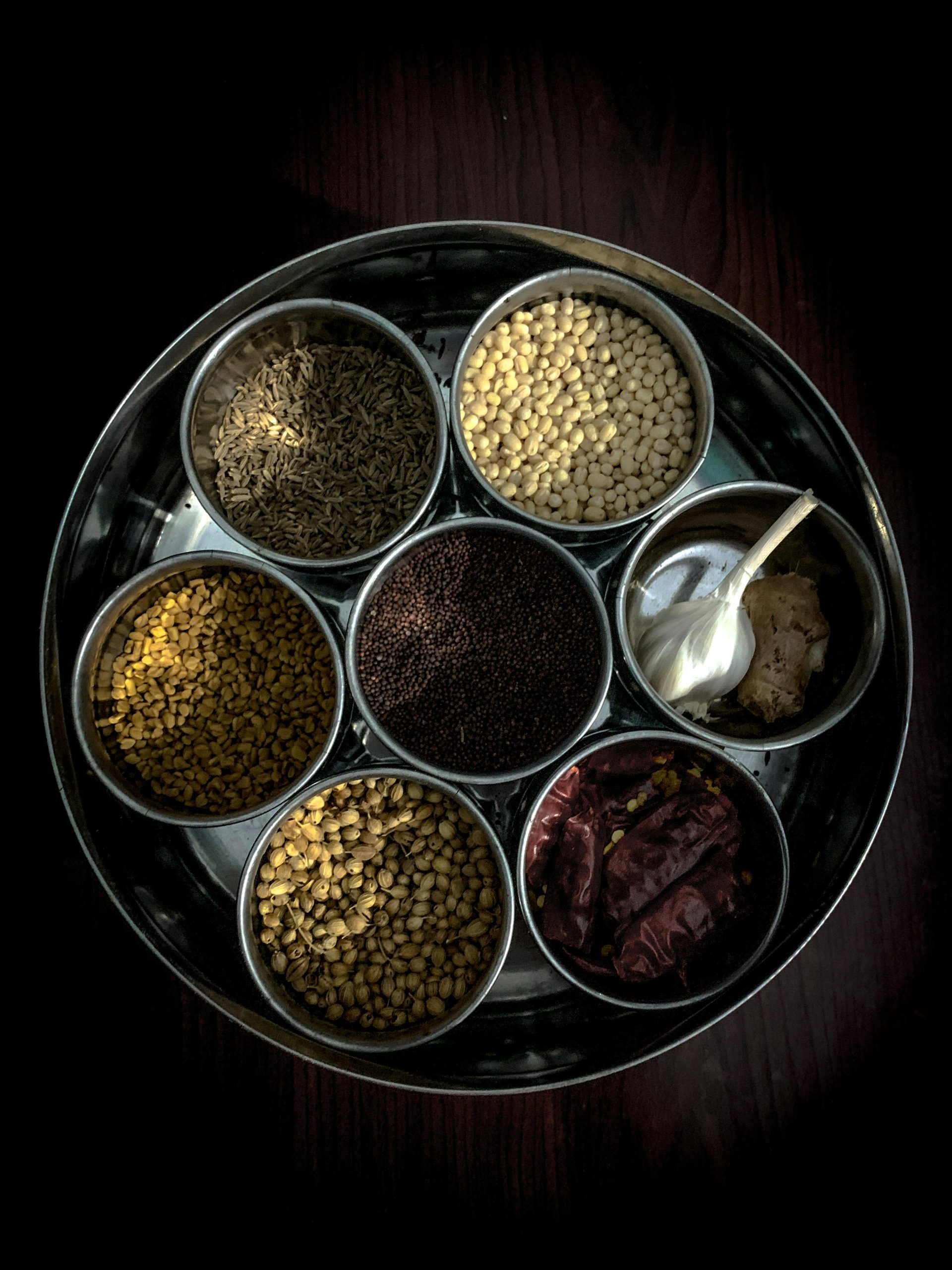 Home Top view of assorted Indian spices in a traditional container, highlighting vibrant textures.